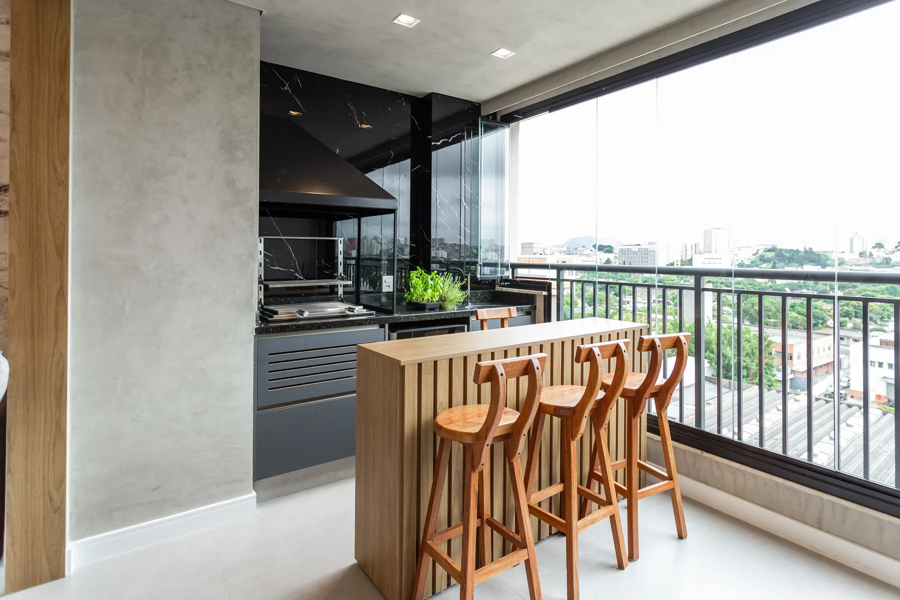 Área gourmet planejada com revestimento em mármore preto, marcenaria em madeira clara e churrasqueira, projeto Linear em apartamento de São Paulo